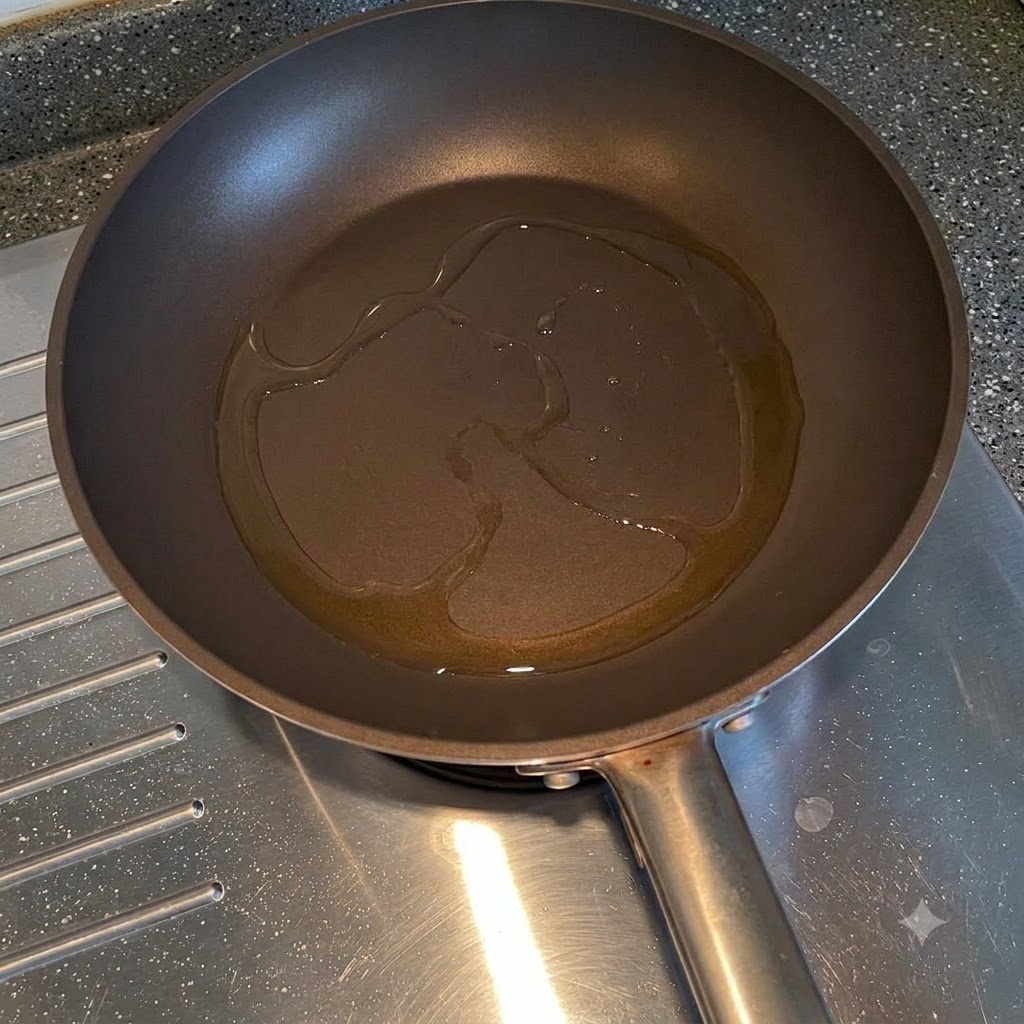 Sliced yellow onions frying in cooking oil inside a pan.