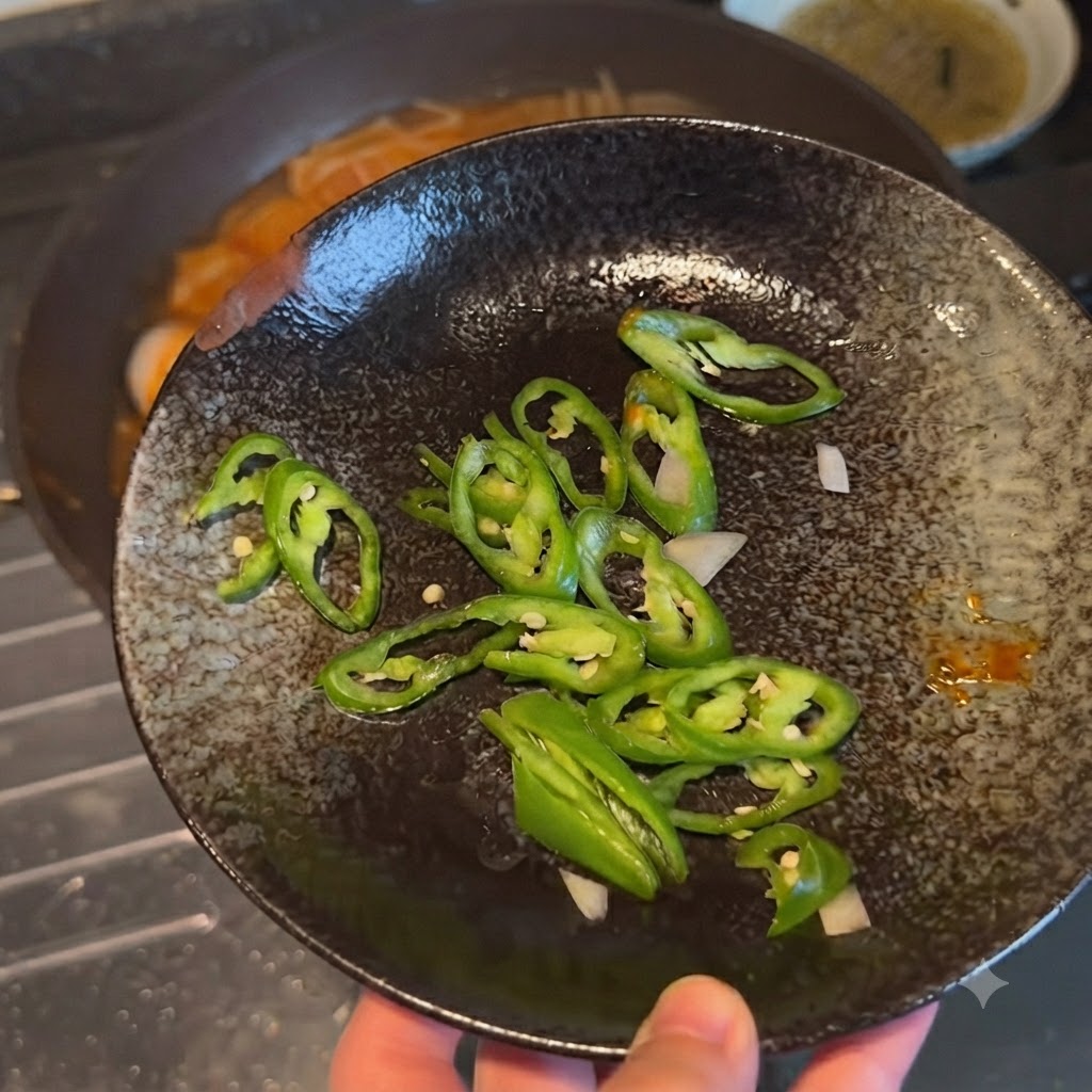 Sliced green chili peppers displayed on a dark decorative plate before being added to the dish.