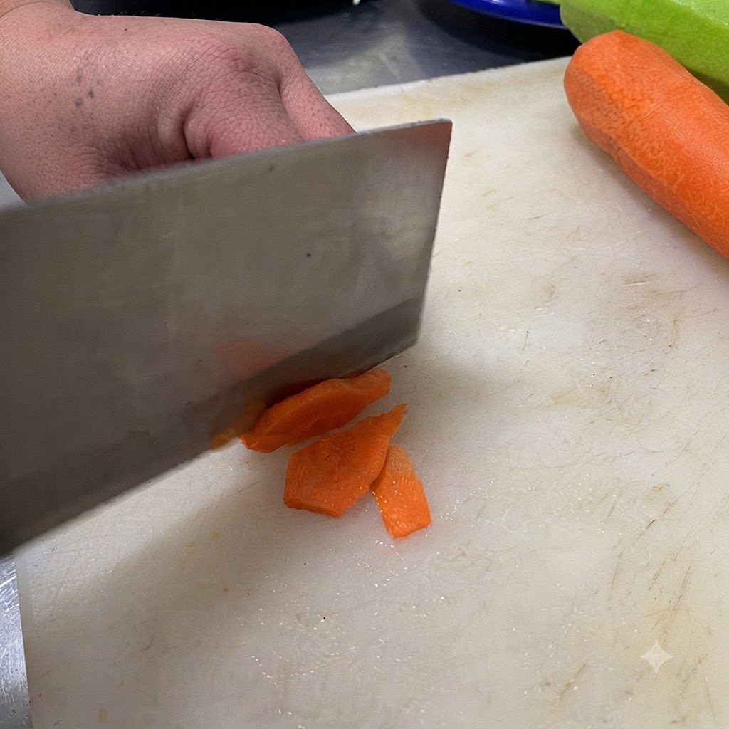 A knife cutting a green chili into slices on a white cutting board.