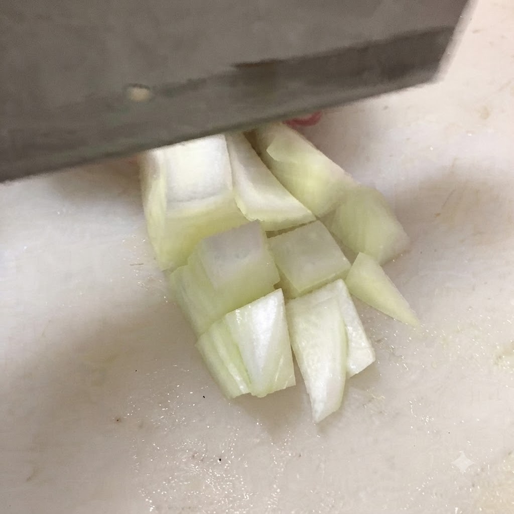 A knife cutting firm tofu into thick cubes on a white cutting board.
