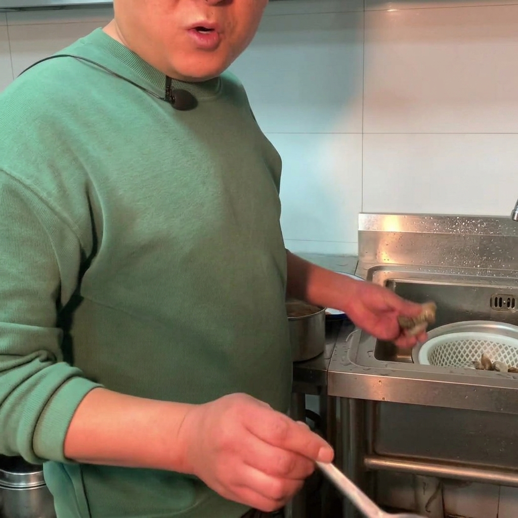 Fresh clams being added into a pot of simmering soybean paste stew.
