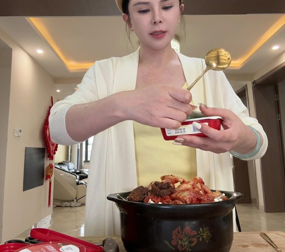 Chopped cabbage being added into the black clay pot on top of the oysters.