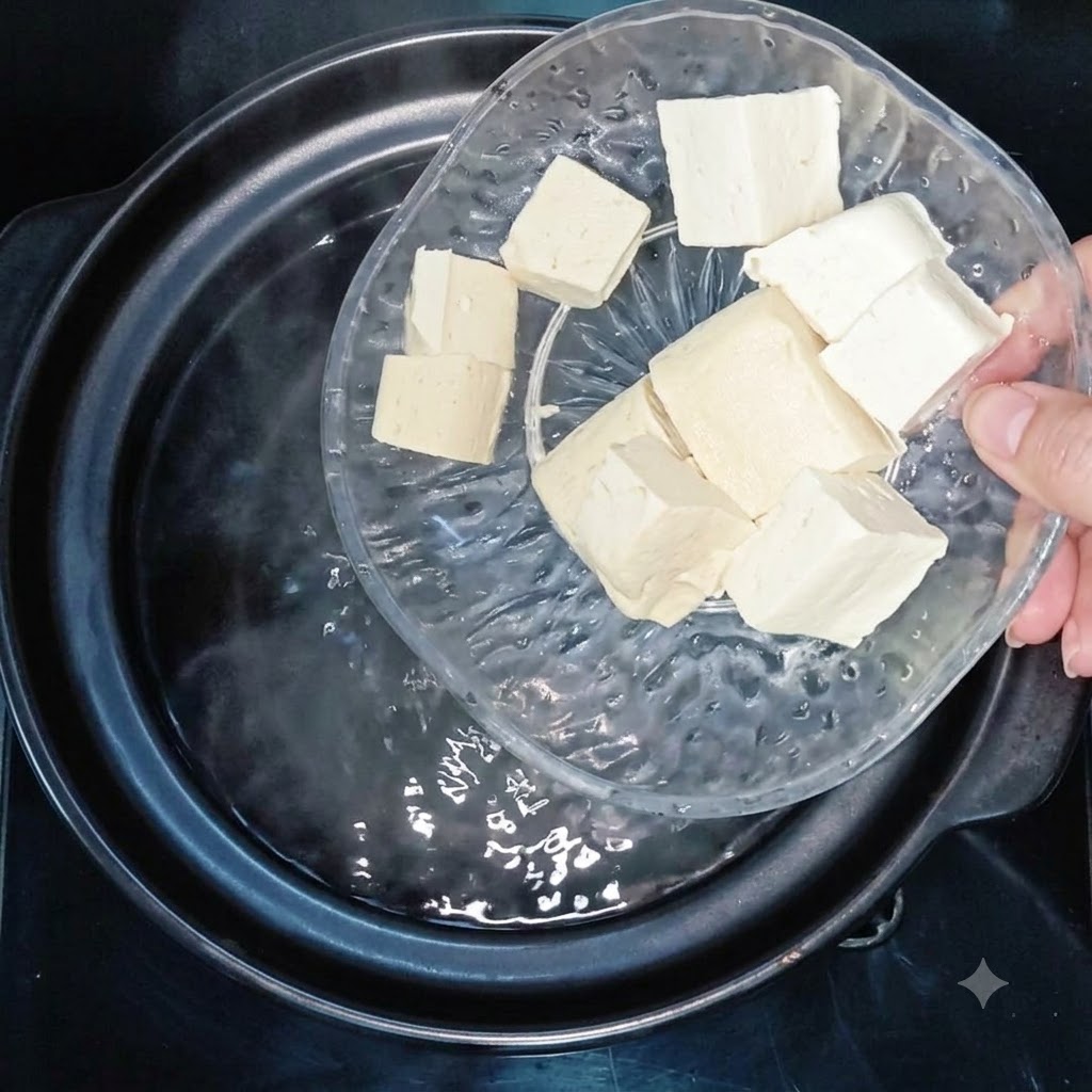 Tofu cubes being added into a pot of boiling water.