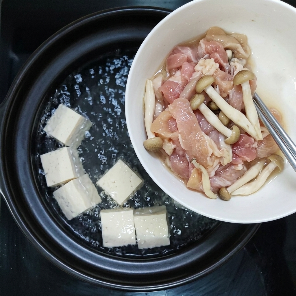 Seasoned pork slices and mushrooms being added together into the boiling pot.