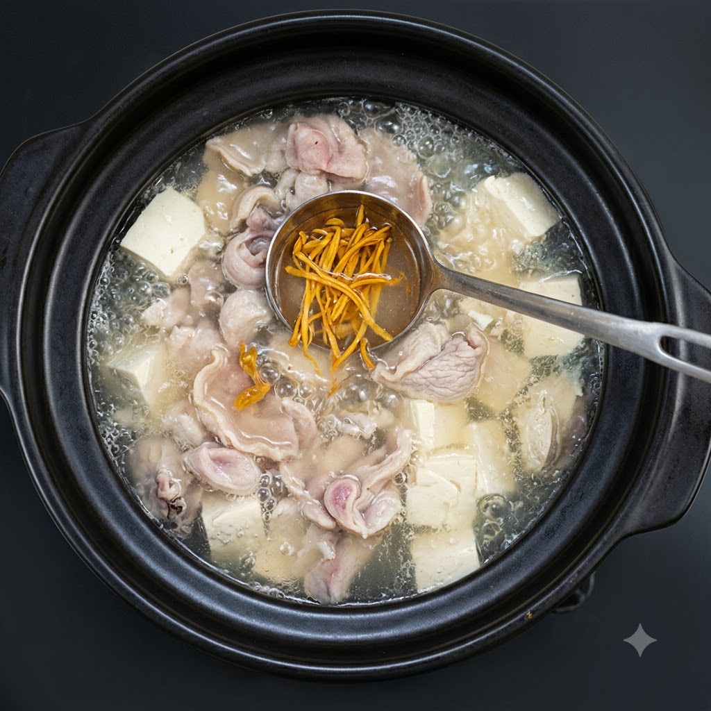 Chopped green onions being sprinkled over the simmering soup in the clay pot.
