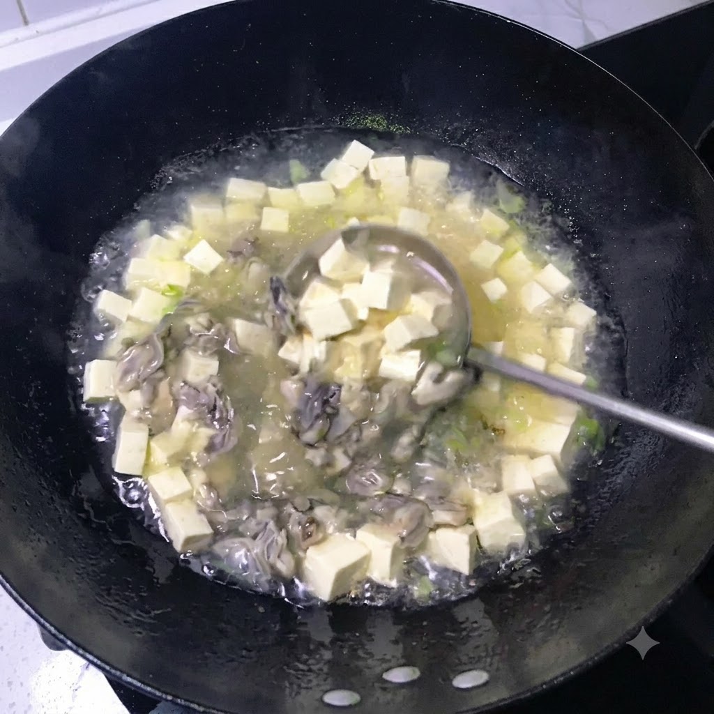 A ladle stirring a simmering milky white broth filled with diced tofu and cooked oysters in a black wok.