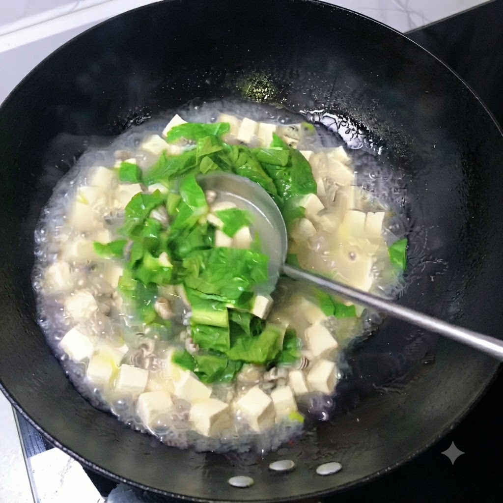 A ladle stirring a milky white broth filled with tofu cubes, oysters, and green leaves in a wok.