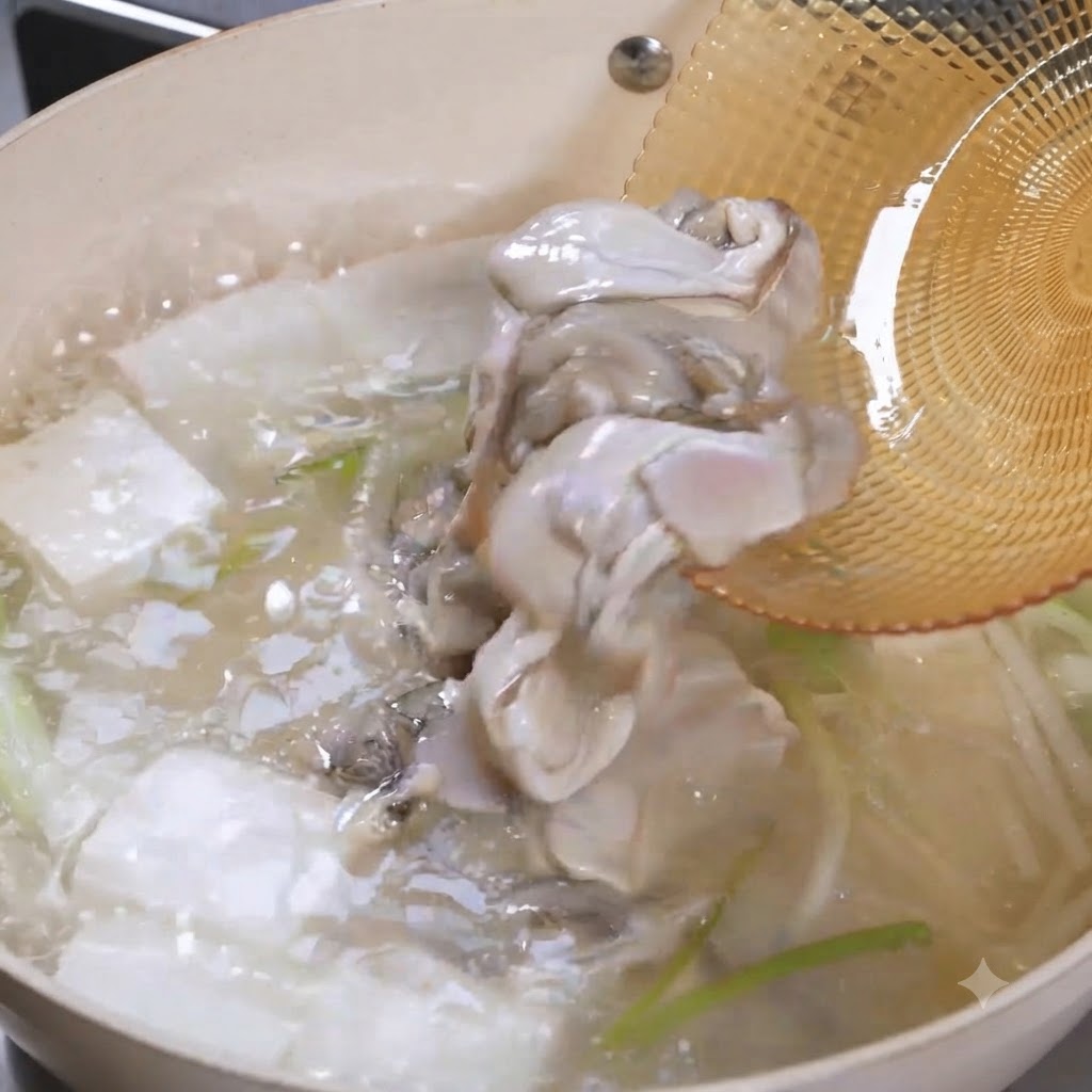 Raw oyster meat sliding off a skimmer into a bubbling pot of tofu soup.