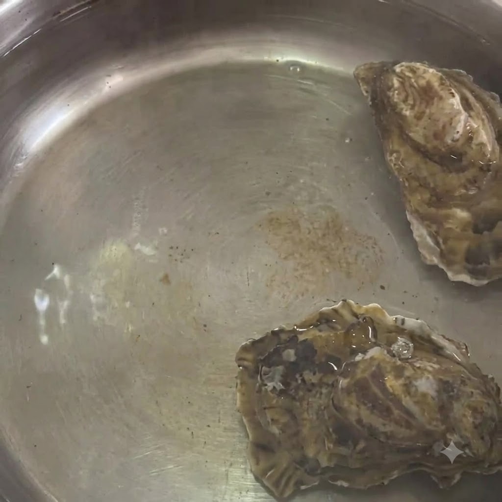 Oysters boiling inside a stainless steel pot of hot water.