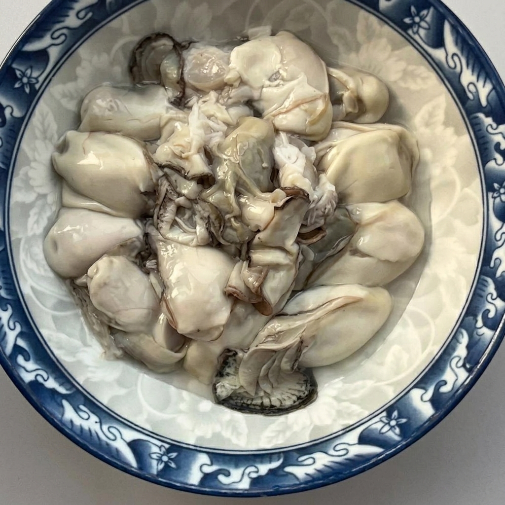 A bowl filled with freshly shelled and rinsed raw oysters.