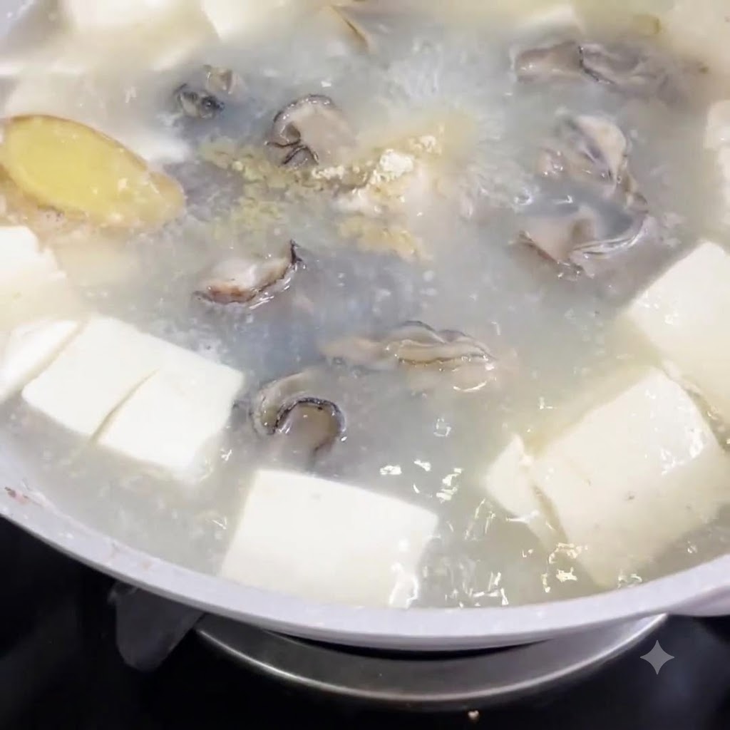 White pepper powder being sprinkled into a pot of boiling soup with tofu cubes and oysters.