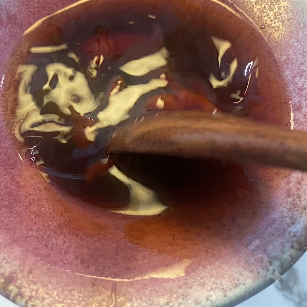 The teriyaki sauce mixture being stirred with a wooden spoon in the bowl.