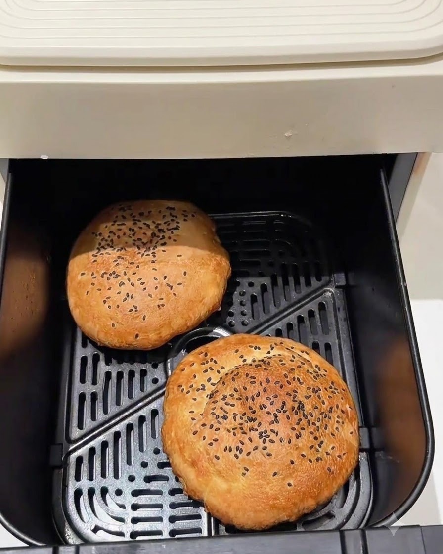 Baked burger buns sitting inside an air fryer basket.