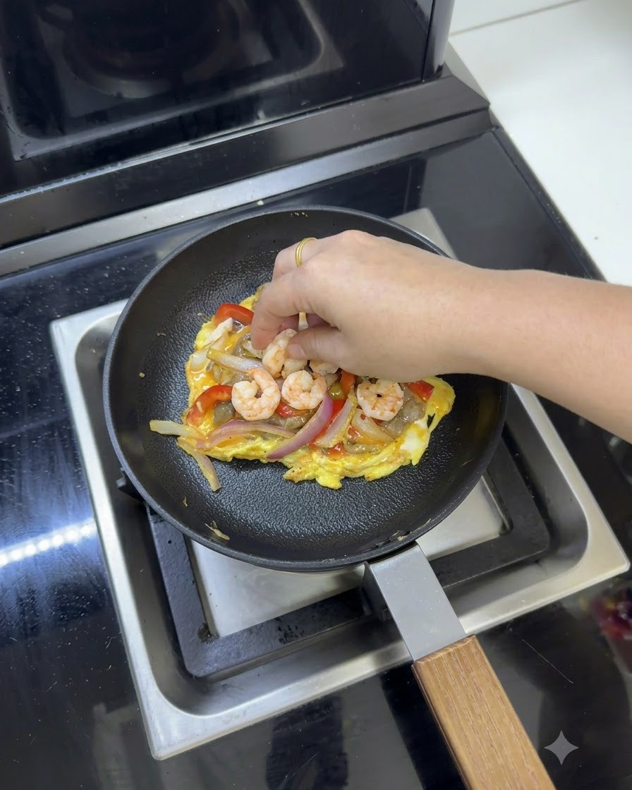 Meltable cheese slices being placed on top of the egg and vegetable mixture in the frying pan.