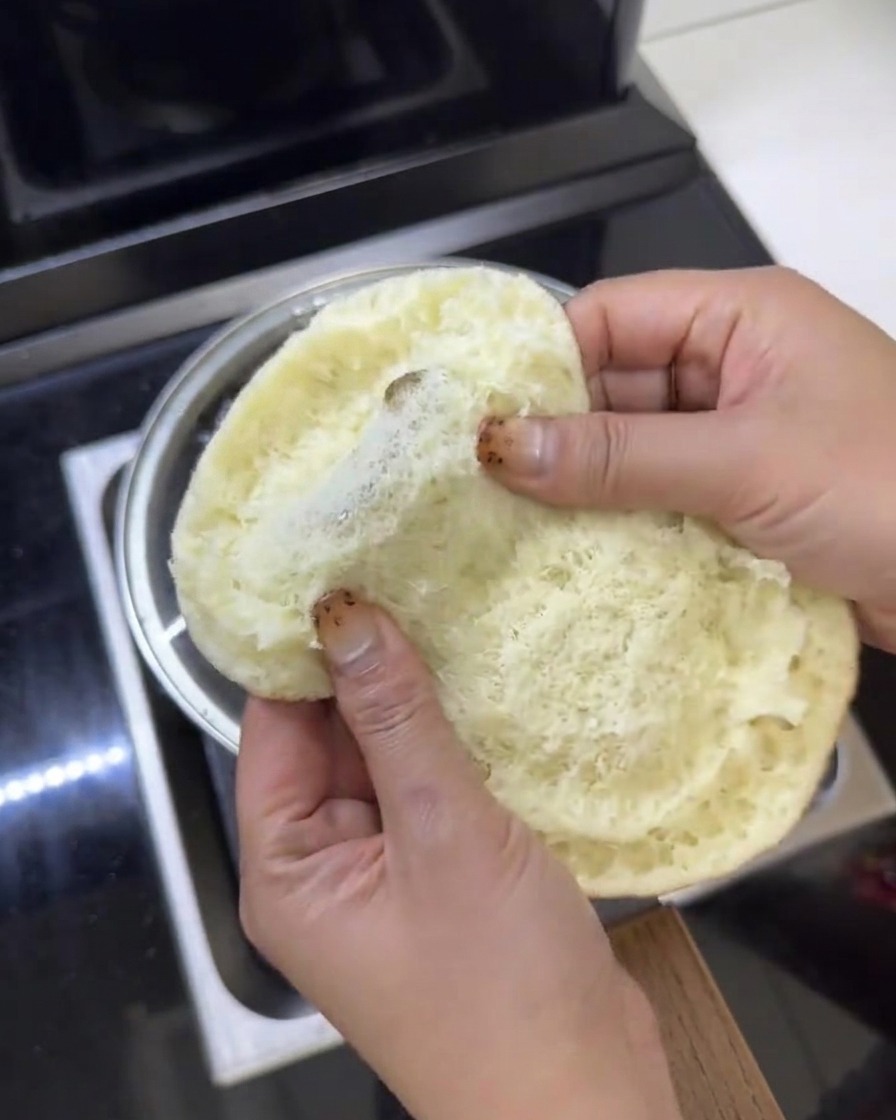 Fresh green lettuce leaves being placed inside an opened butter burger bun.