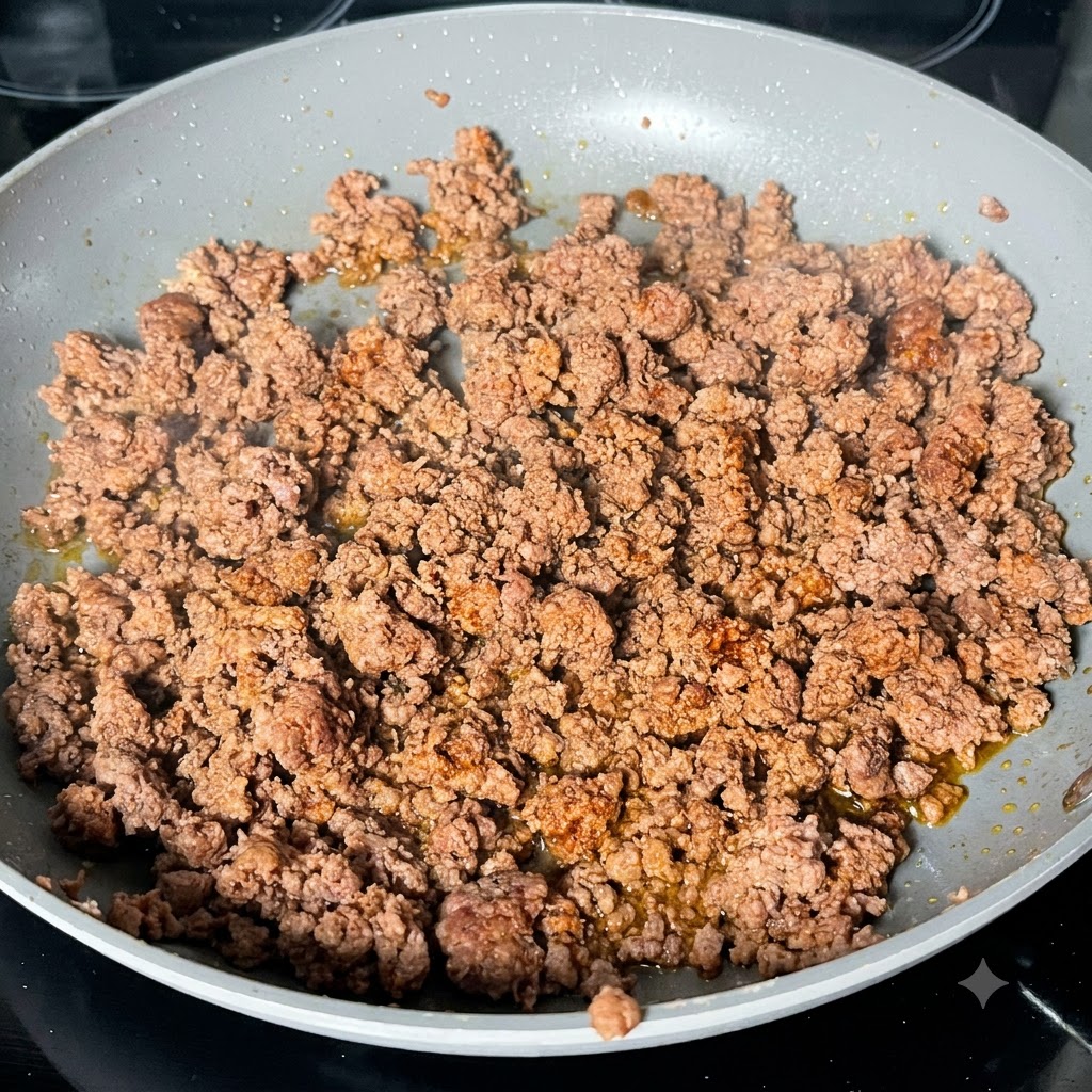 Dark Worcestershire sauce being drizzled over browned beef mince in a pan.