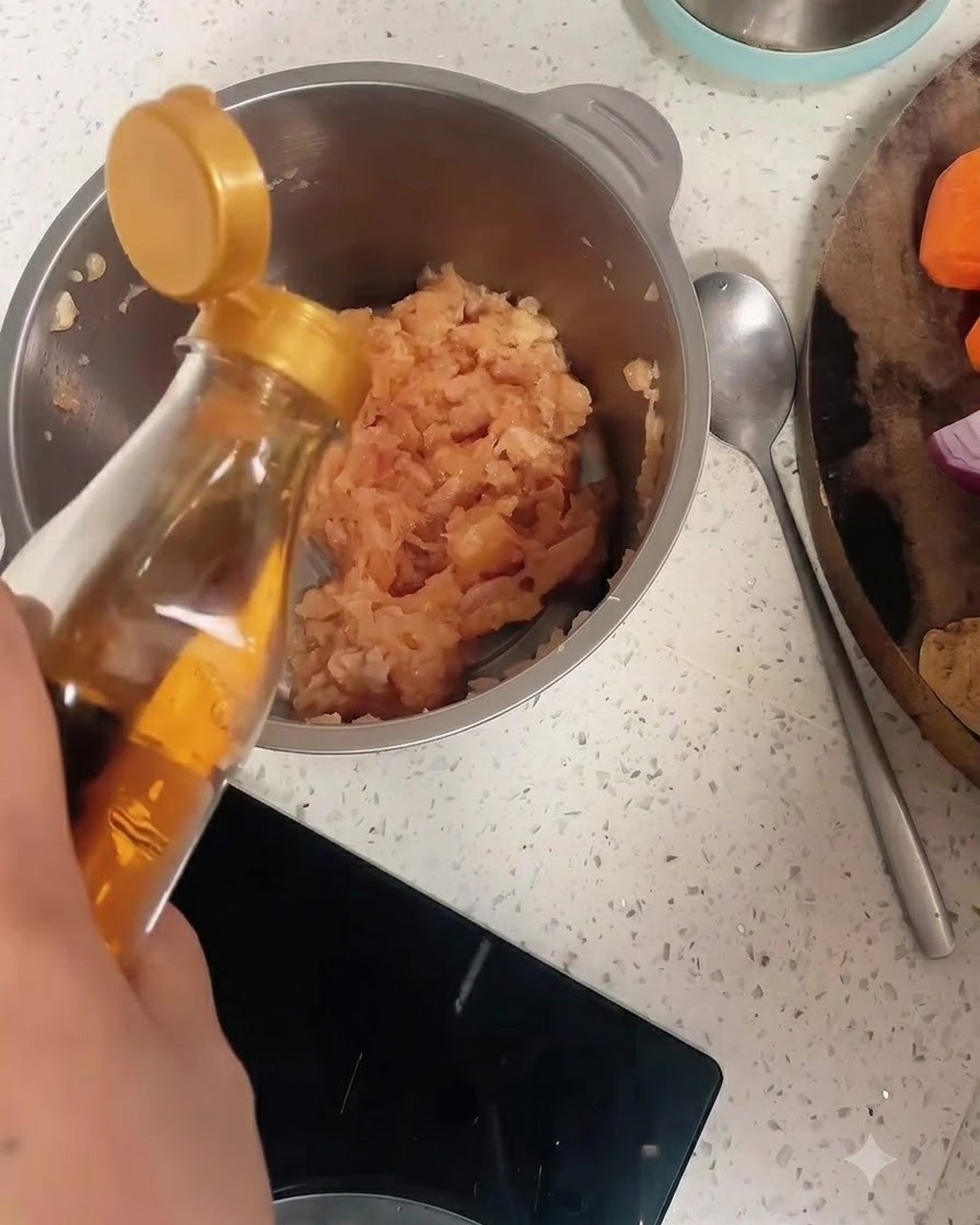 Cooking wine being poured from a bottle into a stainless steel bowl filled with minced chicken and pepper.