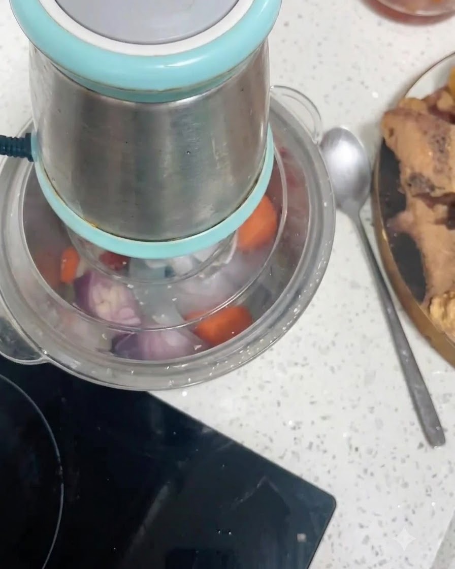 Carrot chunks and red onion pieces inside a food processor container being chopped.