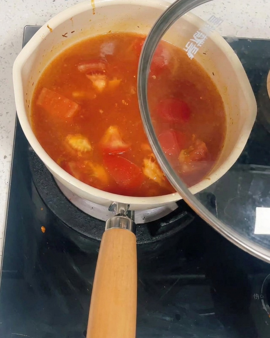 A pot filled with tomato and chicken sauce being covered with a glass lid.