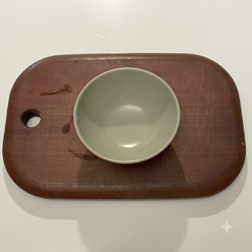 A dark sauce mixture prepared inside a small green ceramic bowl.