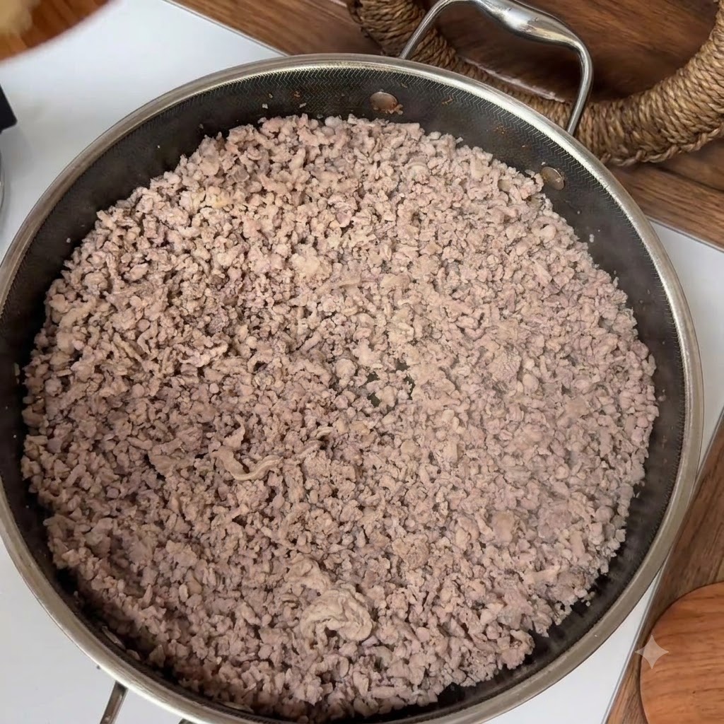 Cooked minced meat filling a stainless steel pan during the stir-frying process.