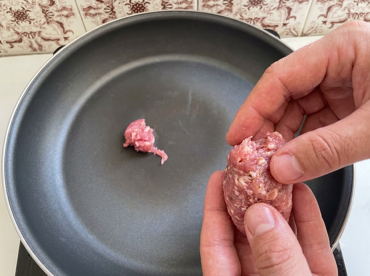 Pieces of Italian sausage meat being arranged and placed into a frying pan.