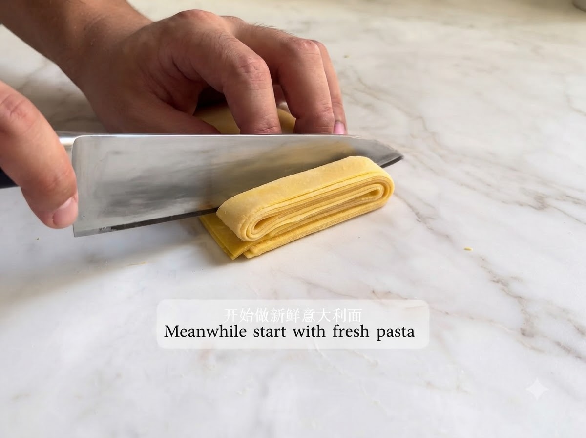 Rolled pasta sheet being folded and cut into strips with a knife.