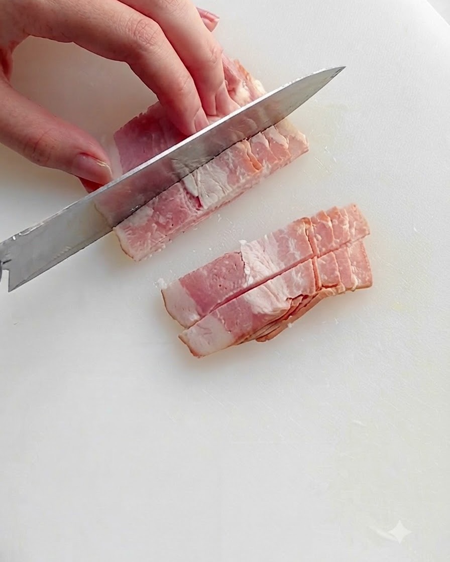 Chopped bacon pieces frying in a hot skillet with oil, showing sizzling fat and browning edges.