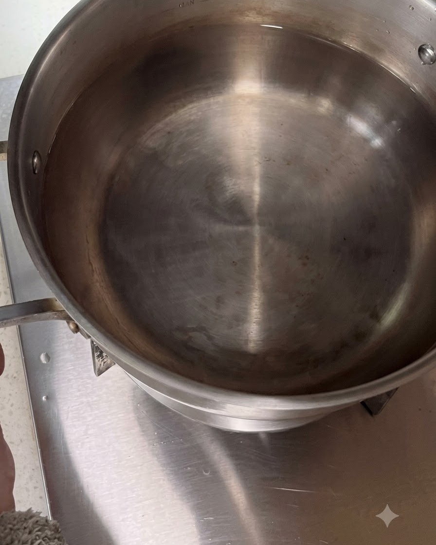 Stainless steel pot filled with water placed on a stovetop burner.