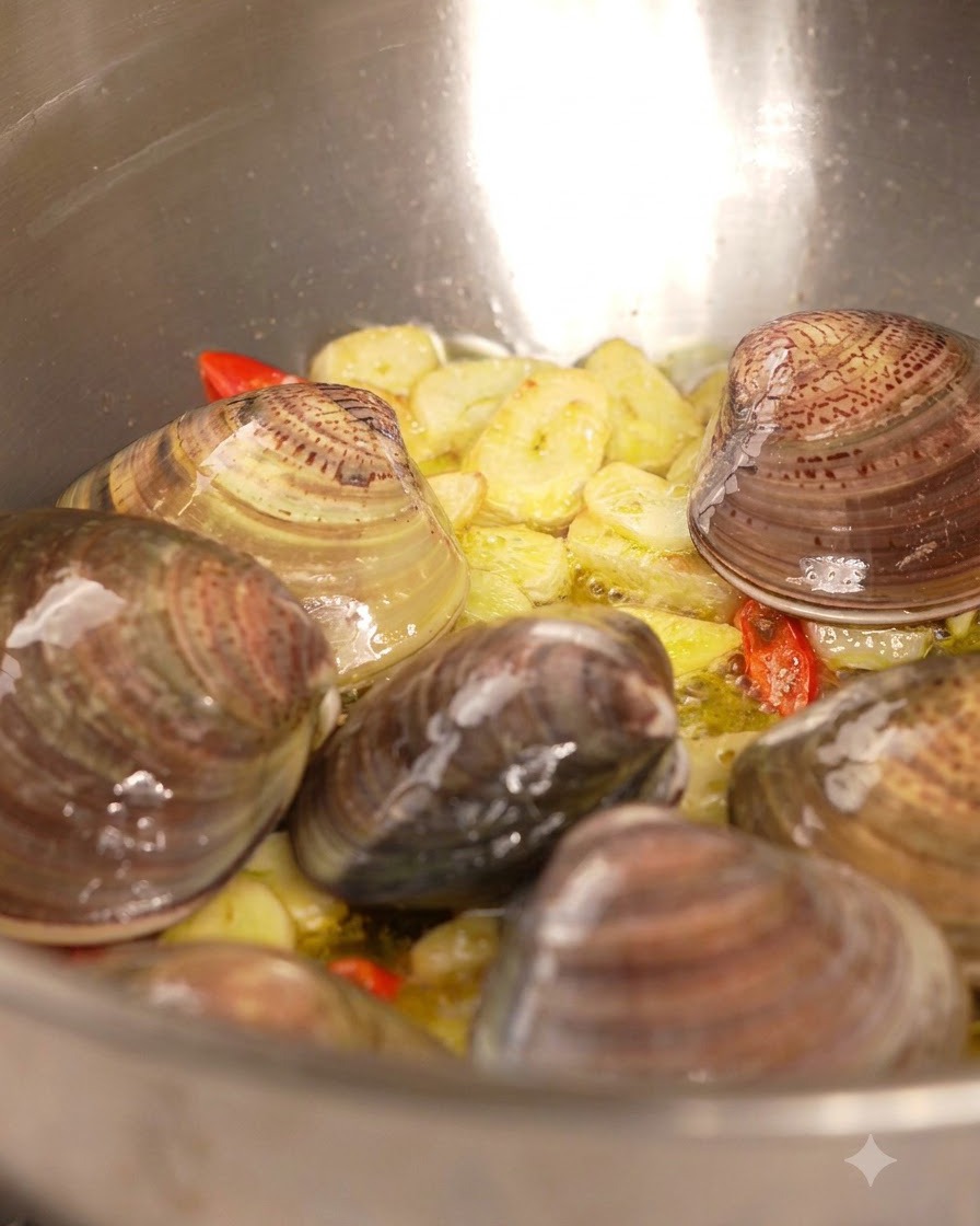 White wine being poured from a bottle into a pan filled with clams, garlic, and chili.