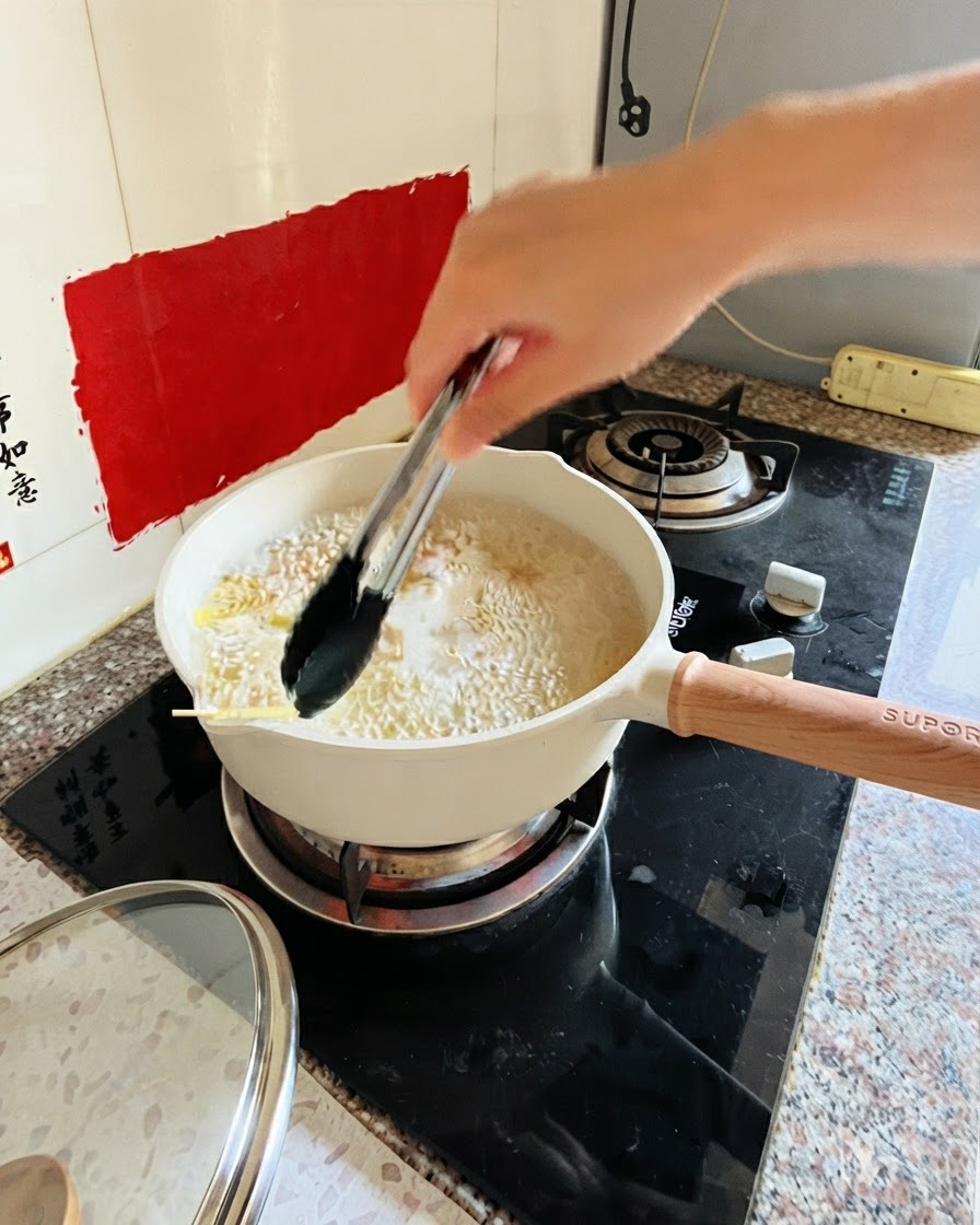 Tongs stirring pasta in a pot of boiling water on the stove.