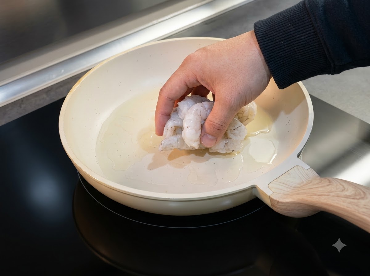 Thawed shrimp being laid out in an oiled pan to cook.