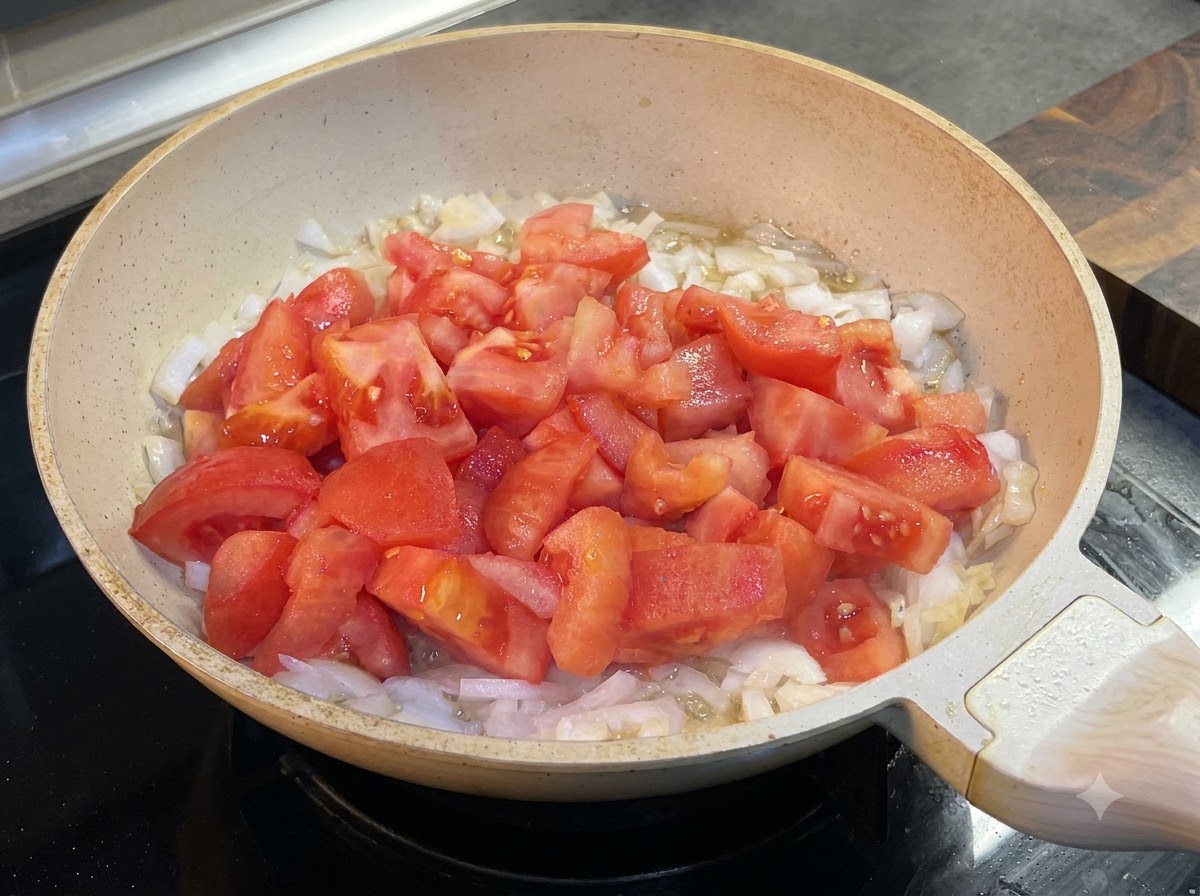Ketchup being added to the pan with tomatoes and onions.