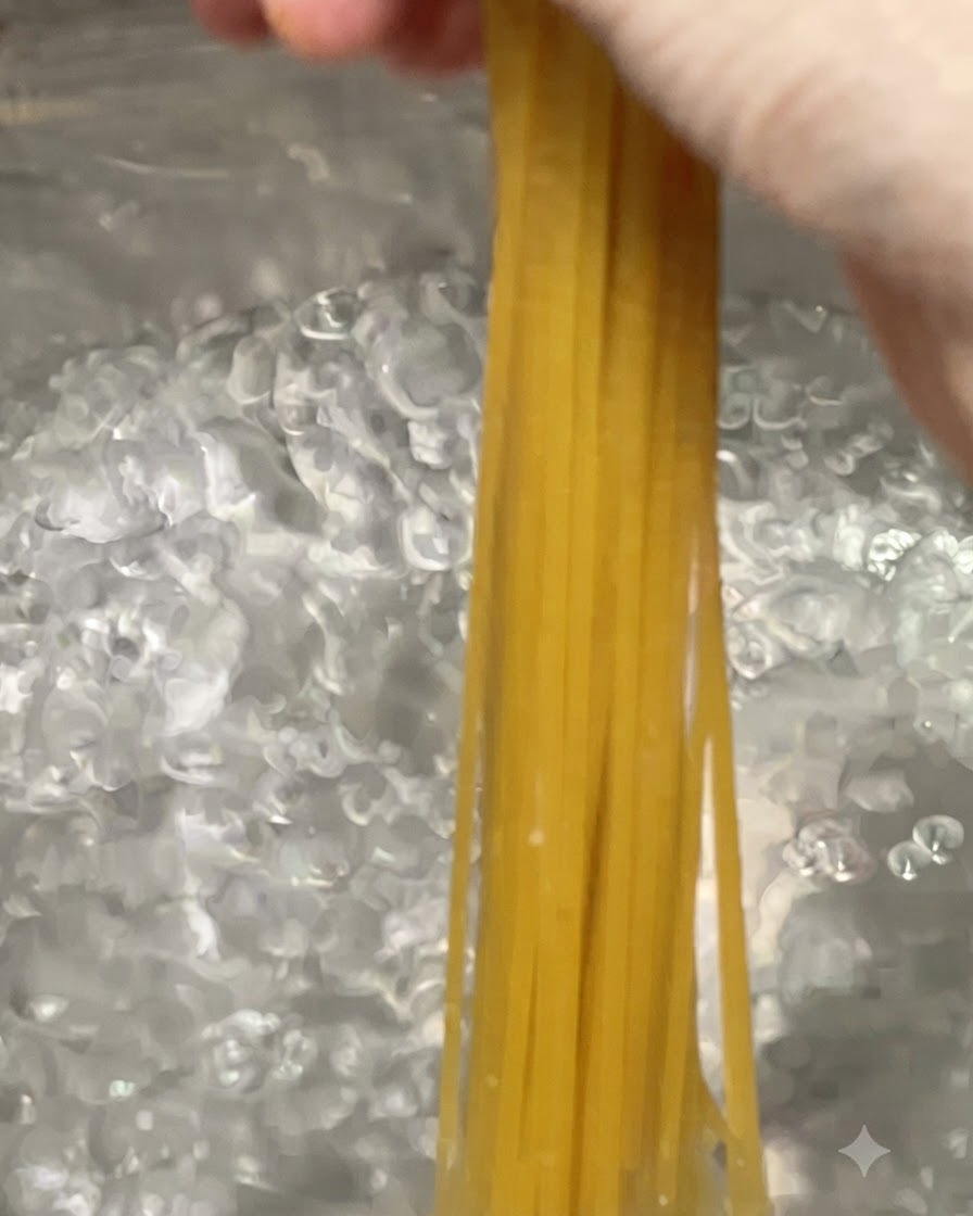 Spaghetti pasta noodles being lowered into a large pot of bubbling boiling water.