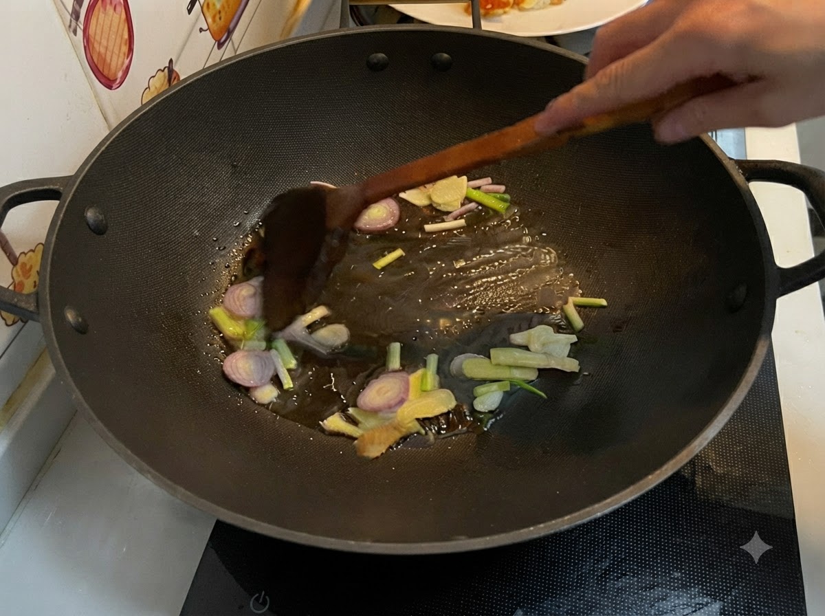 Sliced ginger, garlic, shallot, and scallions frying in hot oil inside a wok, being stirred with a wooden spatula.