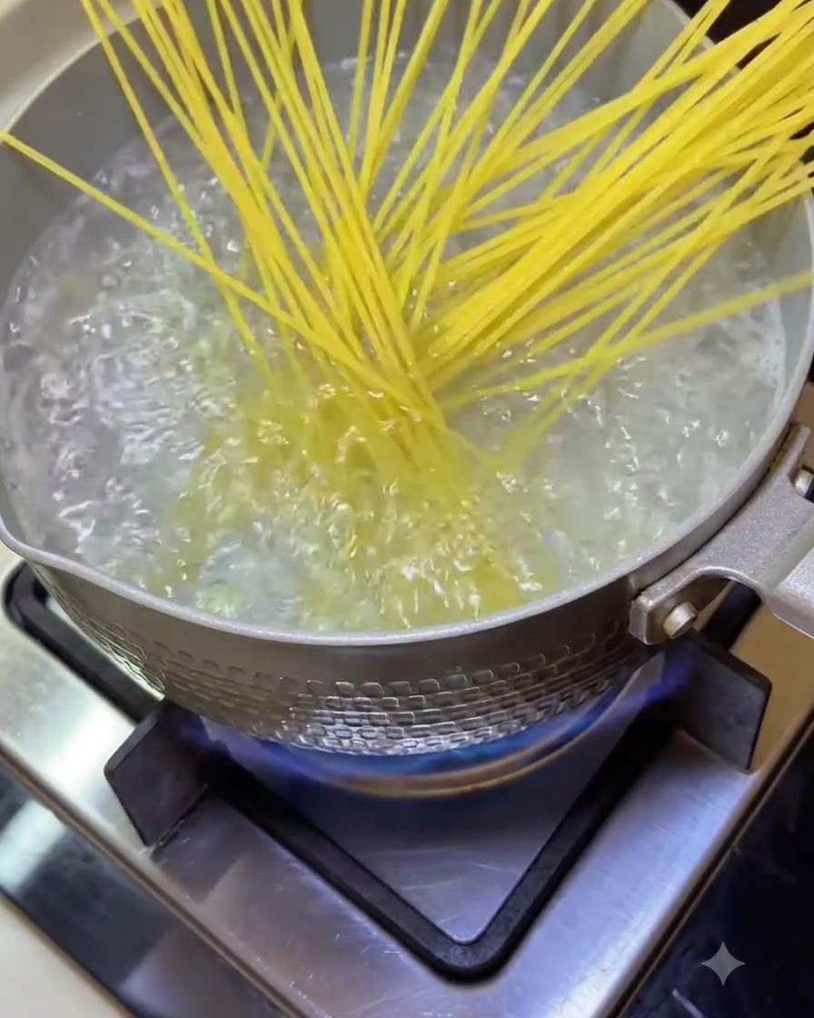Spaghetti noodles being dropped into a pot of bubbling boiling water on the stove.