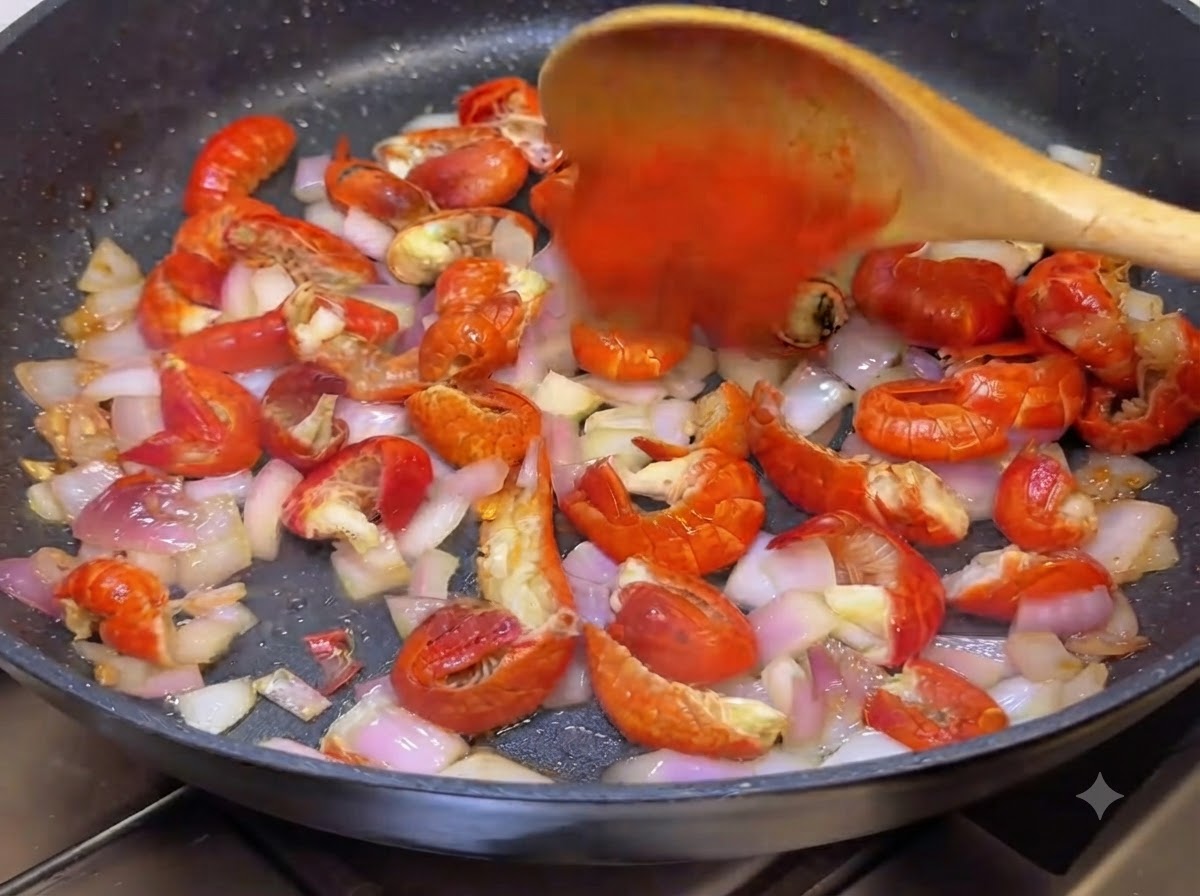 Chili powder and Korean hot sauce being stirred into the pan with a wooden spoon.