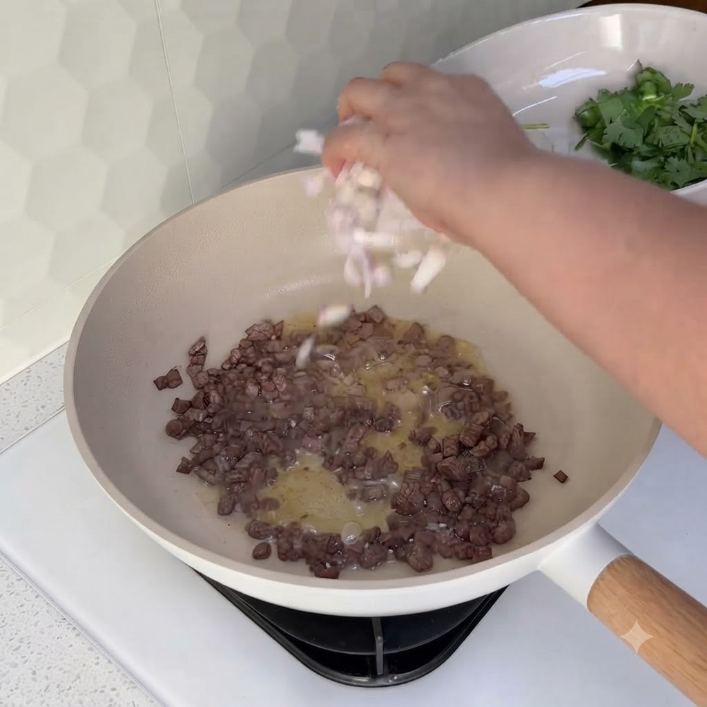 Diced onions being sprinkled into a wok containing cooked minced beef.