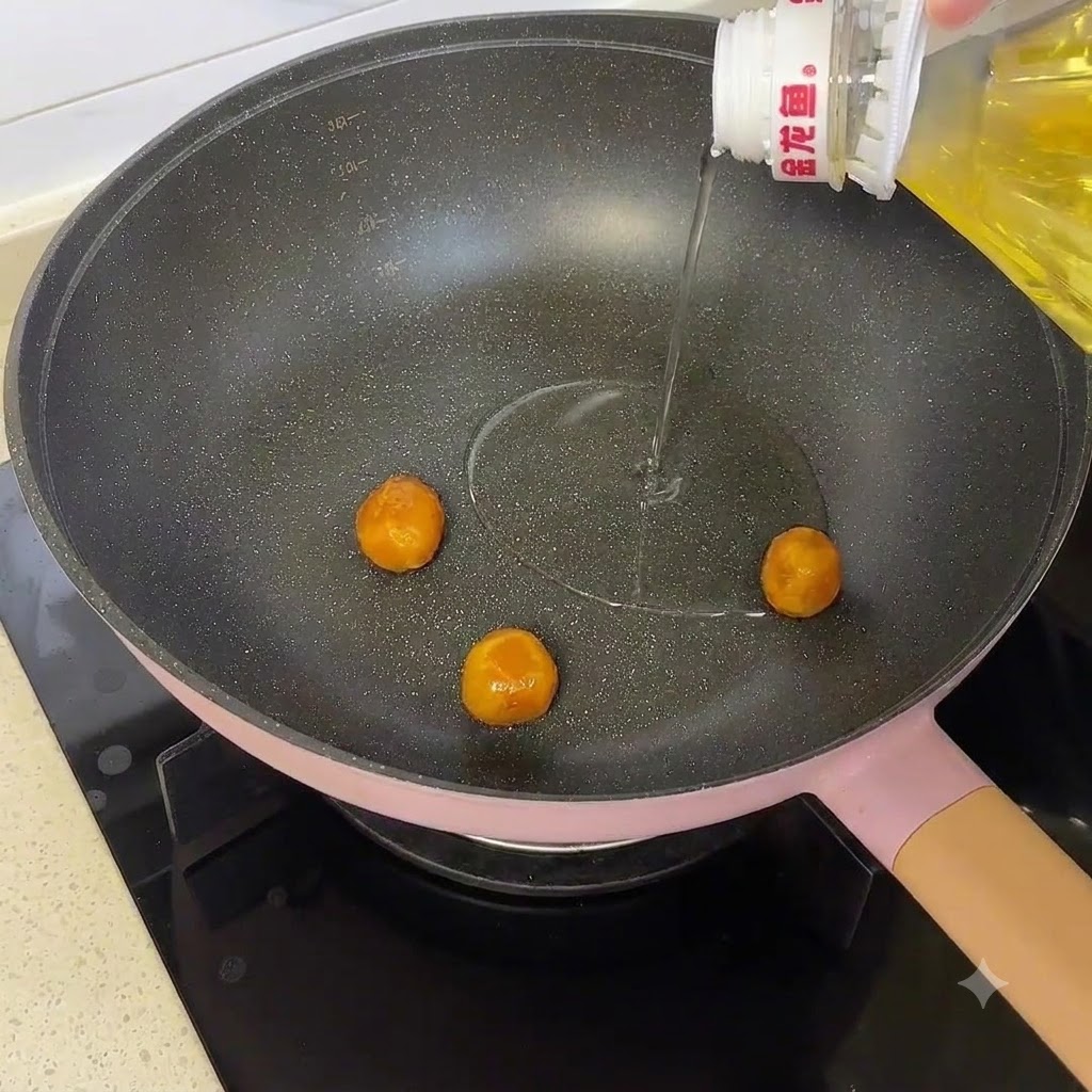 Salted egg yolks cooking in a pan with cooking oil being drizzled from a bottle.