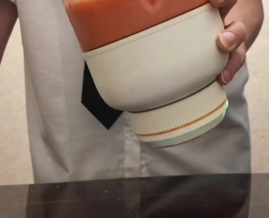 A person holding a portable electric blender filled with smooth, bright red tomato puree.