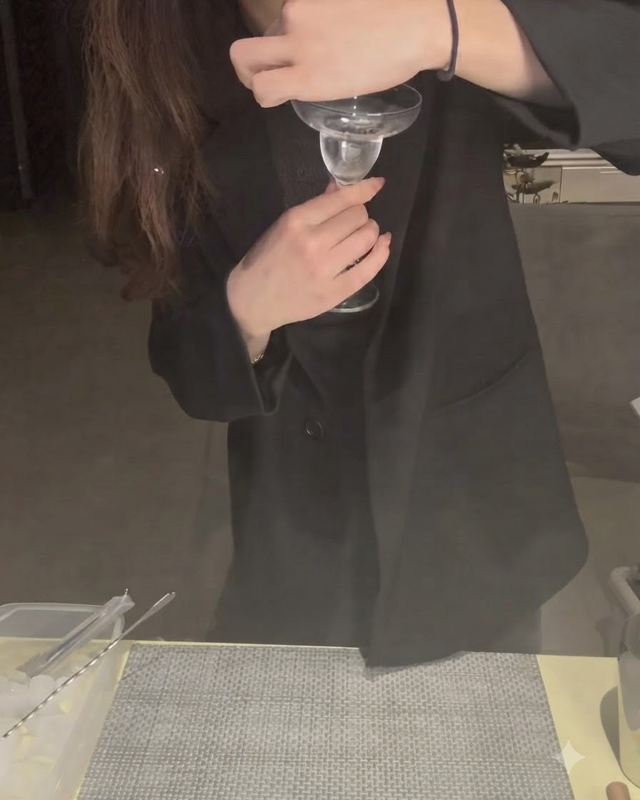 A lime wedge being wiped around the edge of a cocktail glass rim.