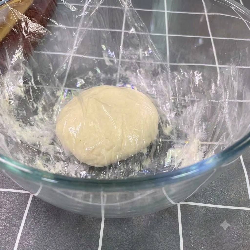 Fermented dough resting and risen to double its size in a large glass bowl.