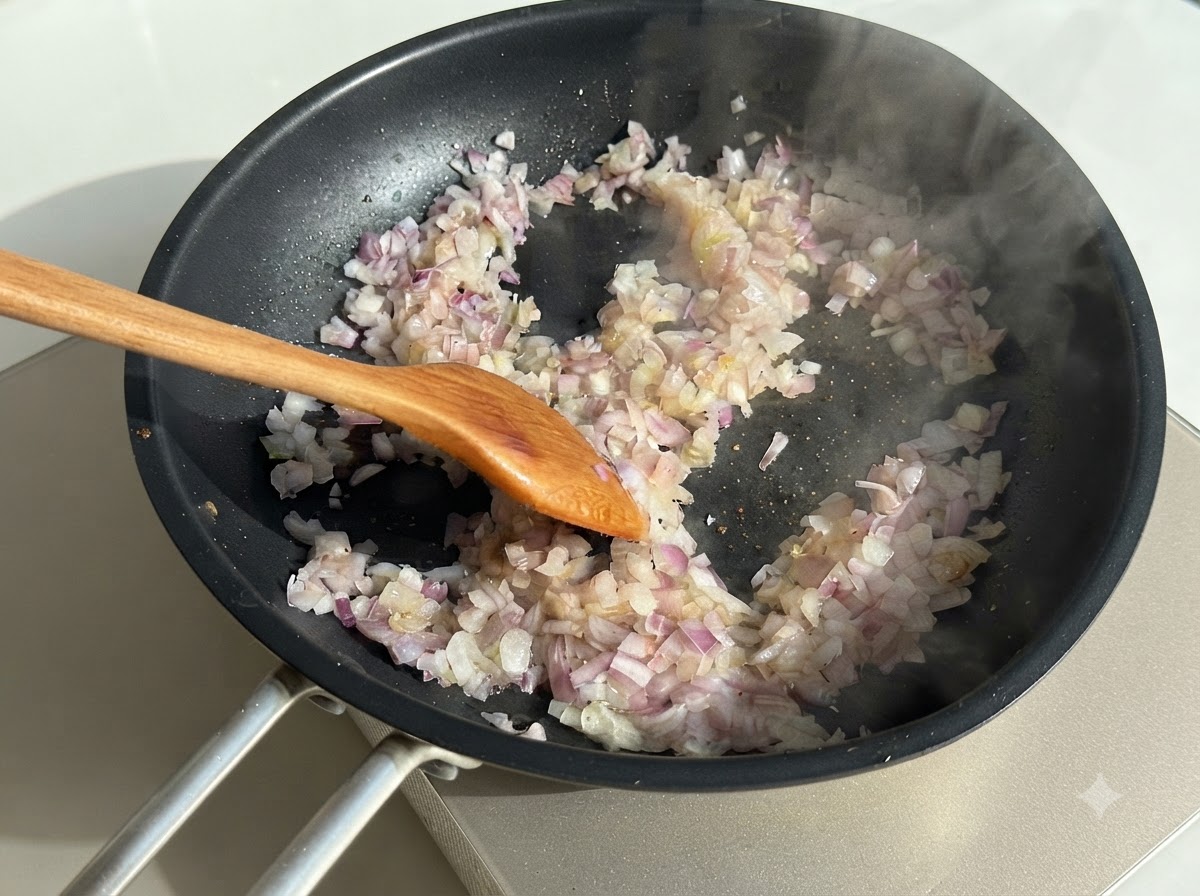 Diced onions being stirred in a hot dark skillet with a wooden spoon, surrounded by wisps of steam.