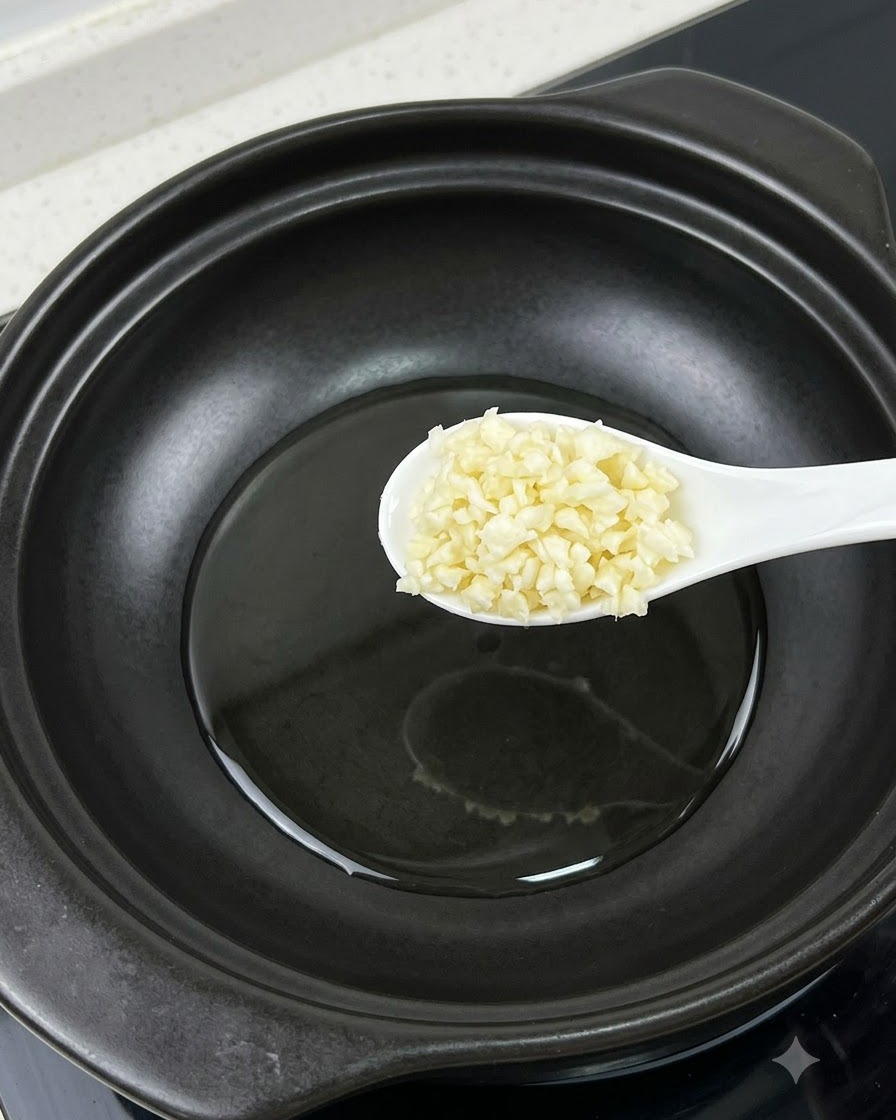 A spoonful of minced garlic held over a pot next to a separated egg yolk.