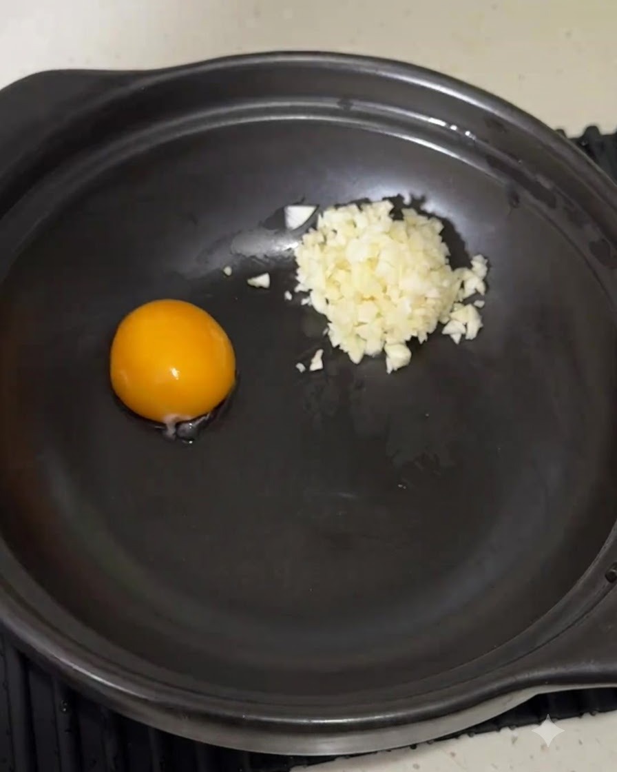 Instant noodle seasoning powder poured into the pot next to the egg yolk and garlic.