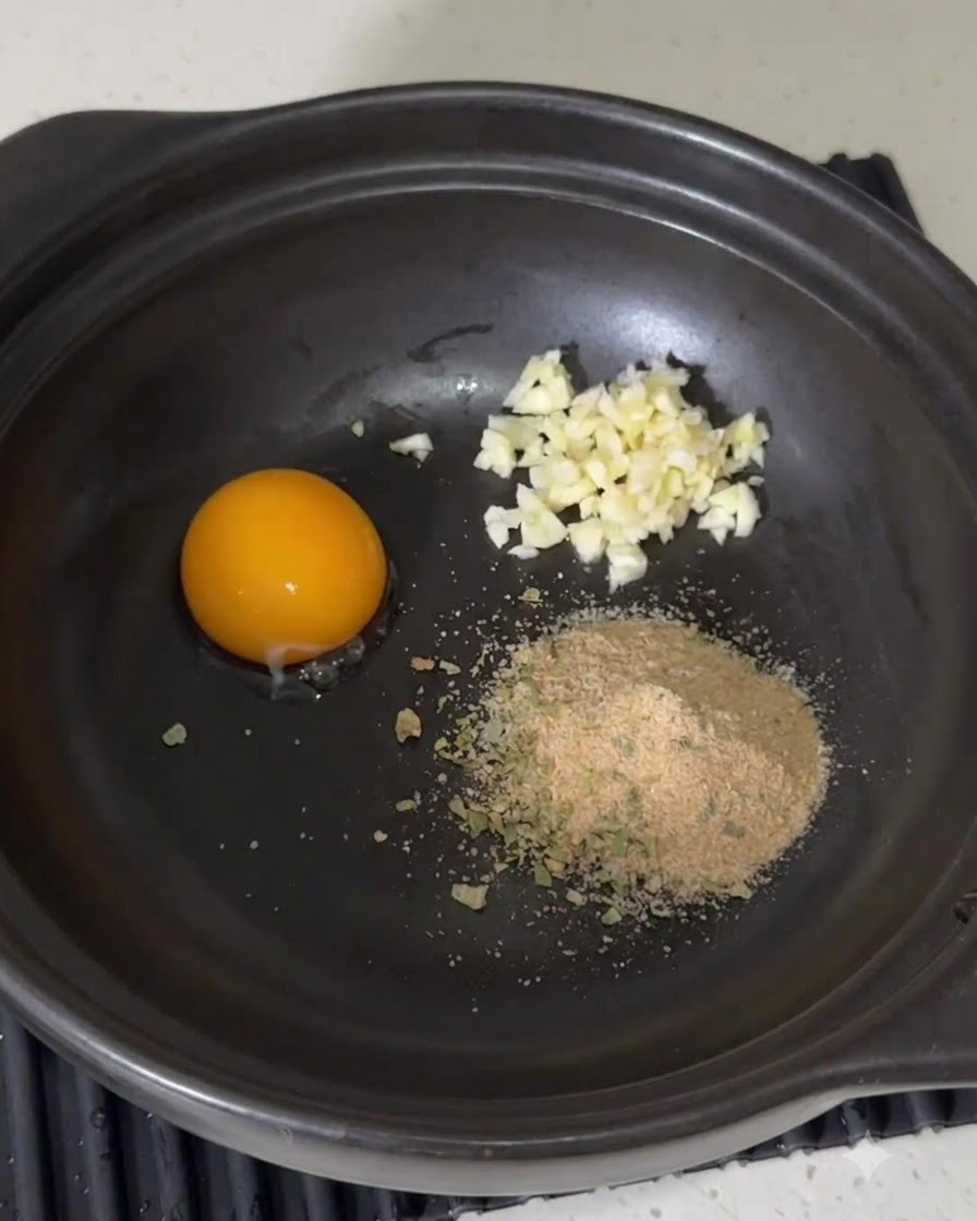 Mayonnaise being squeezed from a bottle into the seasoning mixture inside the pot.