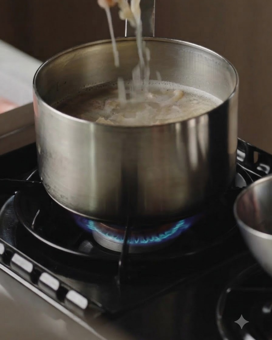 Cooked meat slices being lifted out of a pot of boiling broth with chopsticks.