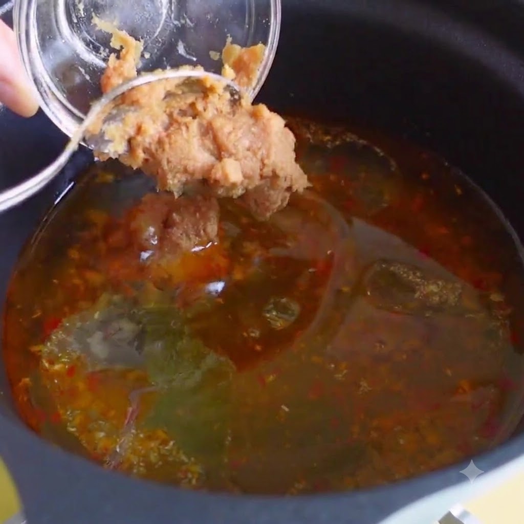 Chicken bouillon, bonito extract, and Korean chili paste being mixed into the soup broth.