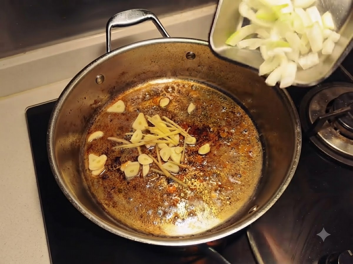 Sliced onions being poured from a small tray into a pan containing garlic and ginger sizzling in oil.