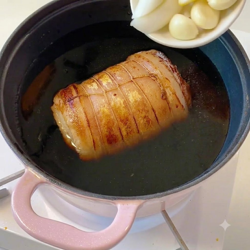 A small white dish holding sliced scallions, ginger pieces, and garlic cloves being emptied into the pot.